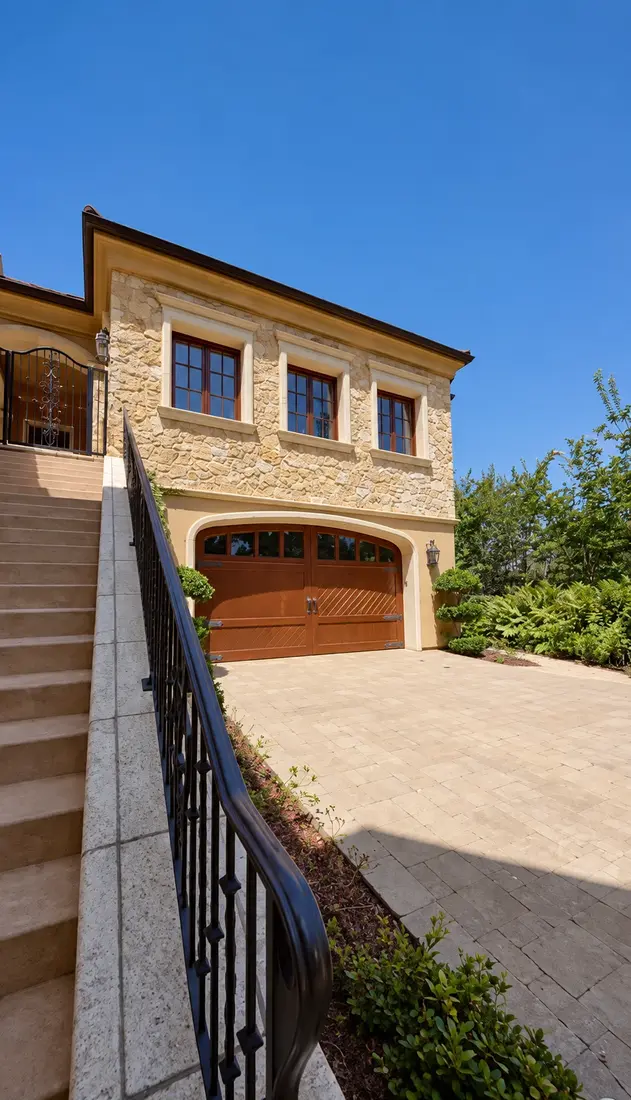 Stone and stucco garage wing with wood carriage doors and cream window trim