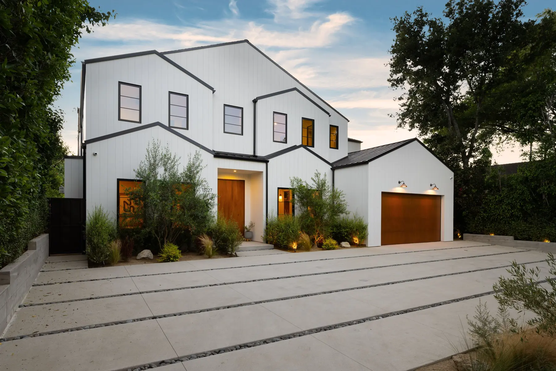 Two-story white board and batten house exterior with black window trim at dusk
